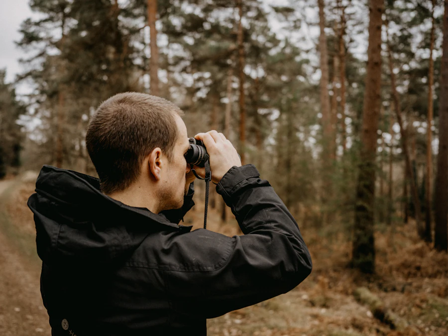 Hunter glassing through binoculars in a pine forest